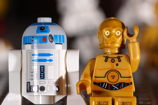 Dos figuras de robot de juguete, una de ellas con la mano en la cabeza en gesto pensativo.